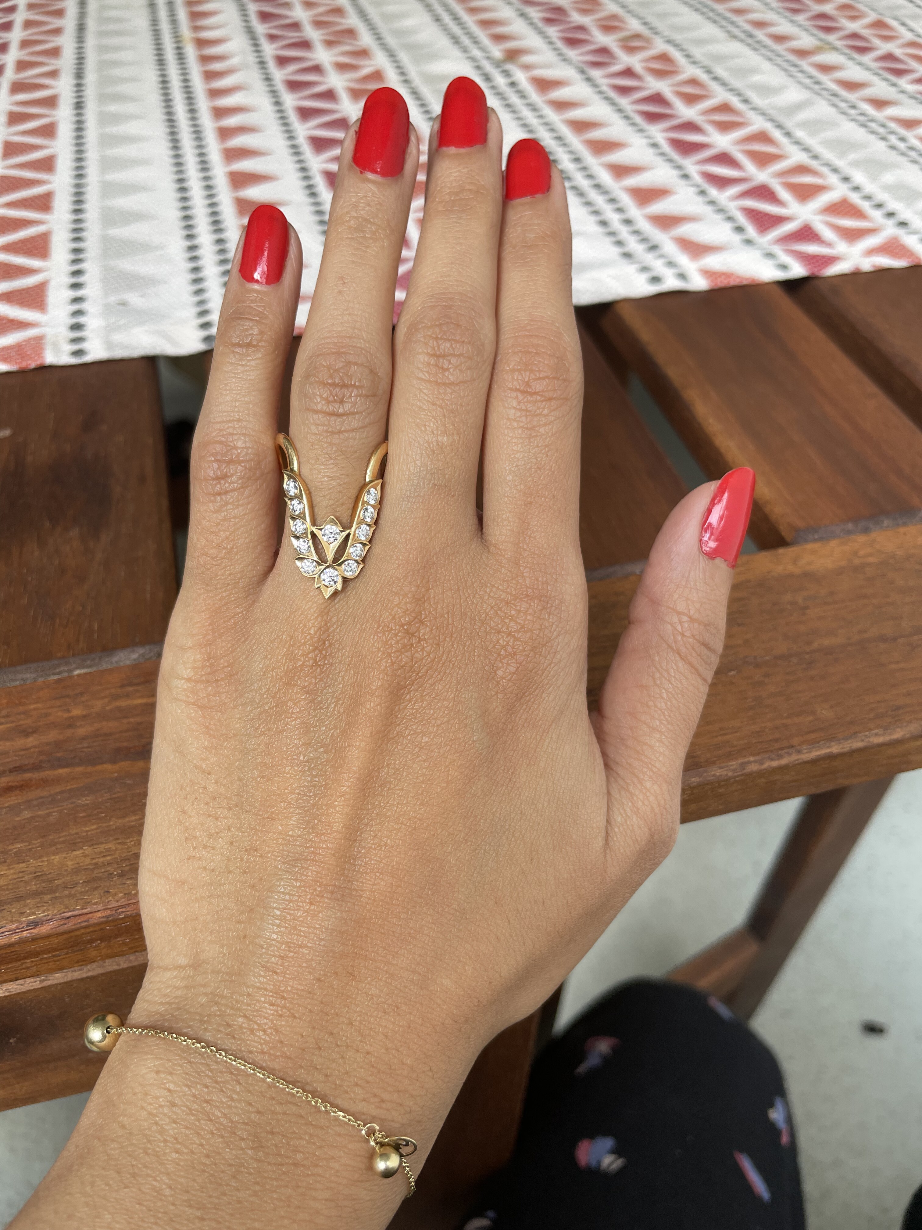 Finished open gold ring with diamond-set leaf details worn on a hand