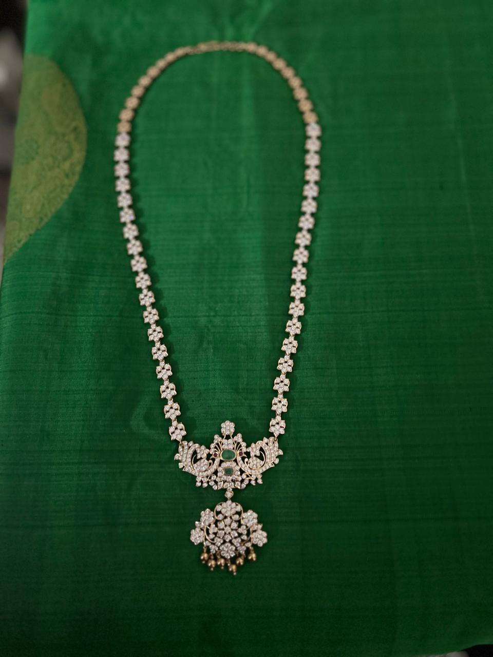 A finished diamond necklace with an ornate pendant, laid out on deep green silk