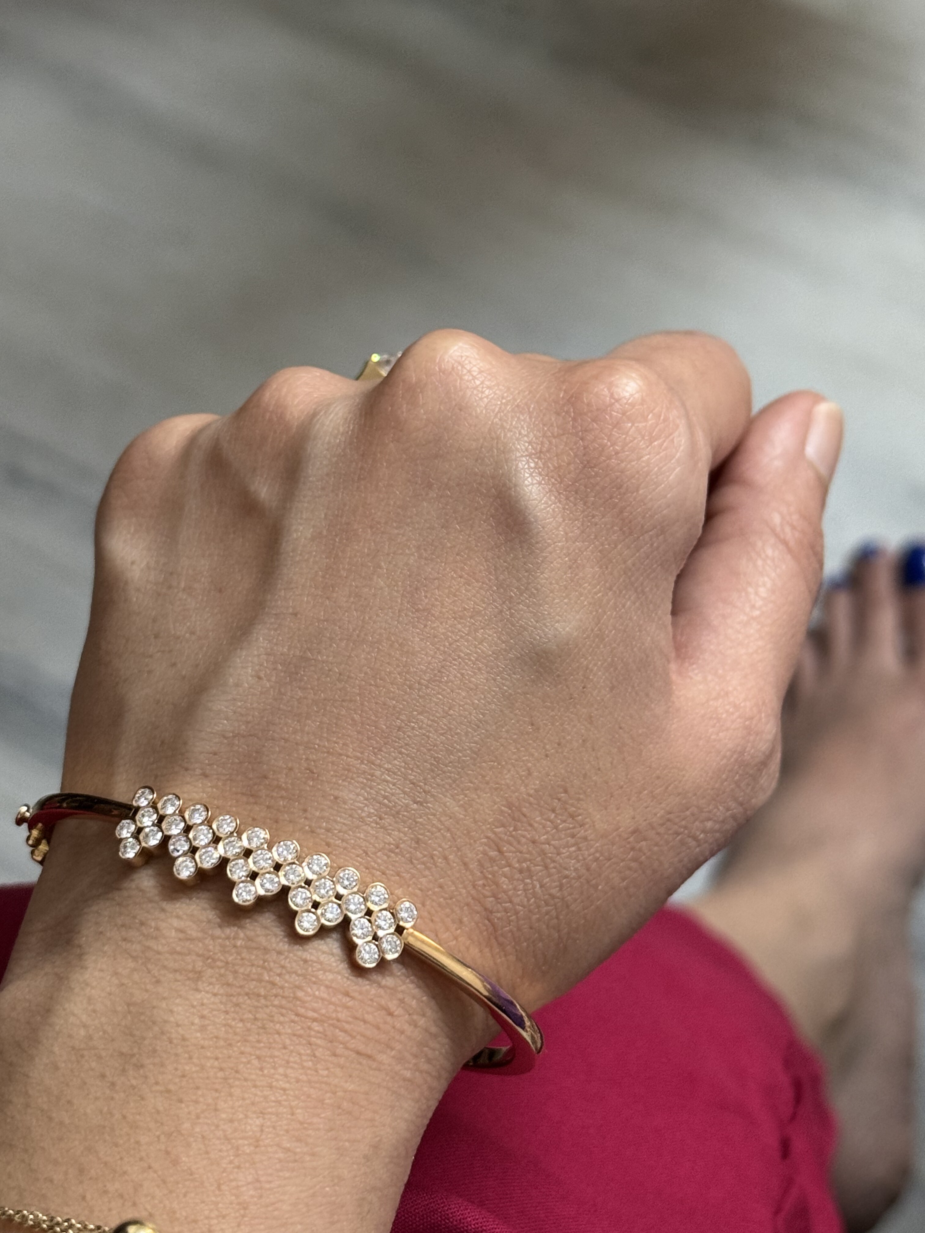 Finished gold bracelet with clustered round diamond flowers worn on a wrist