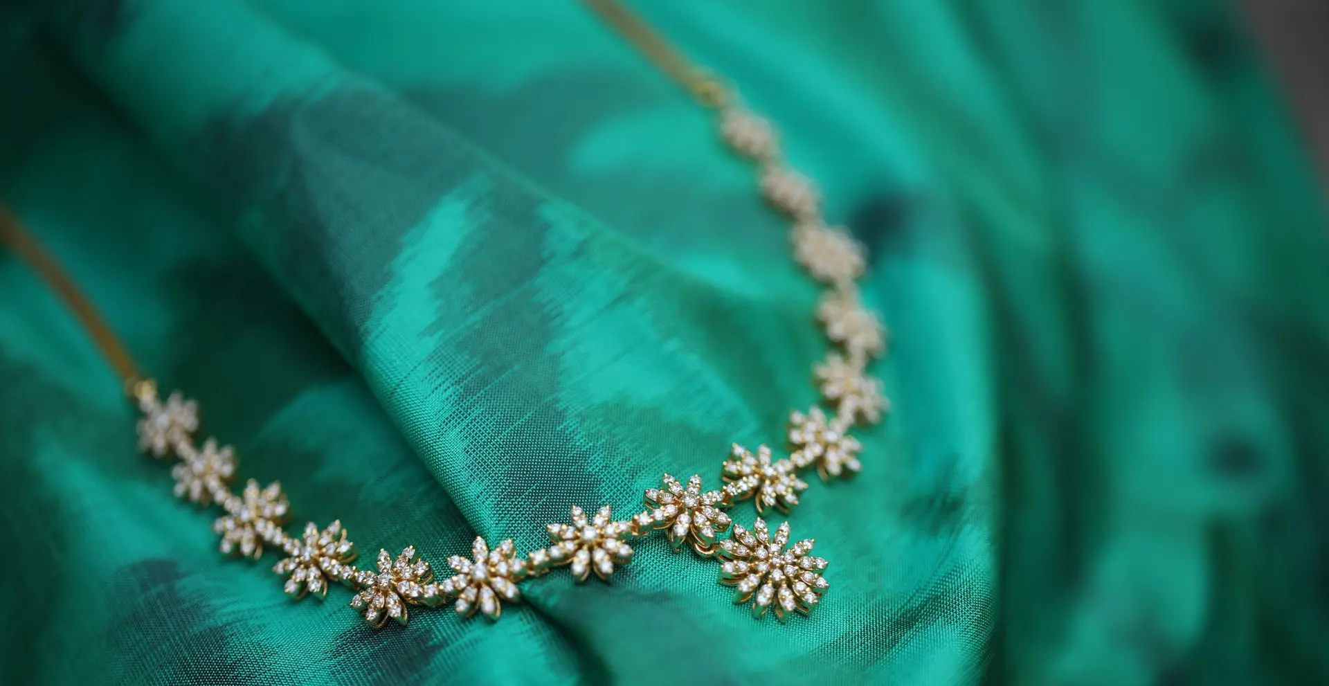 Floral diamond necklace arranged on emerald green silk